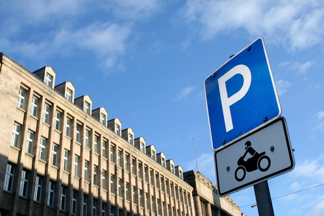 Sininen P-pysäköintimerkki ja moottoripyörätunnus kaupunkirakennuksen edustalla.
